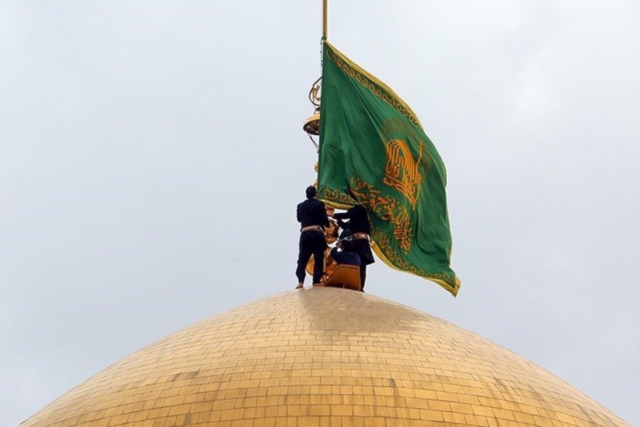 تصویر برافراشته شدن پرچم سبز رضوی بر گنبد حرم امام رضا(ع)